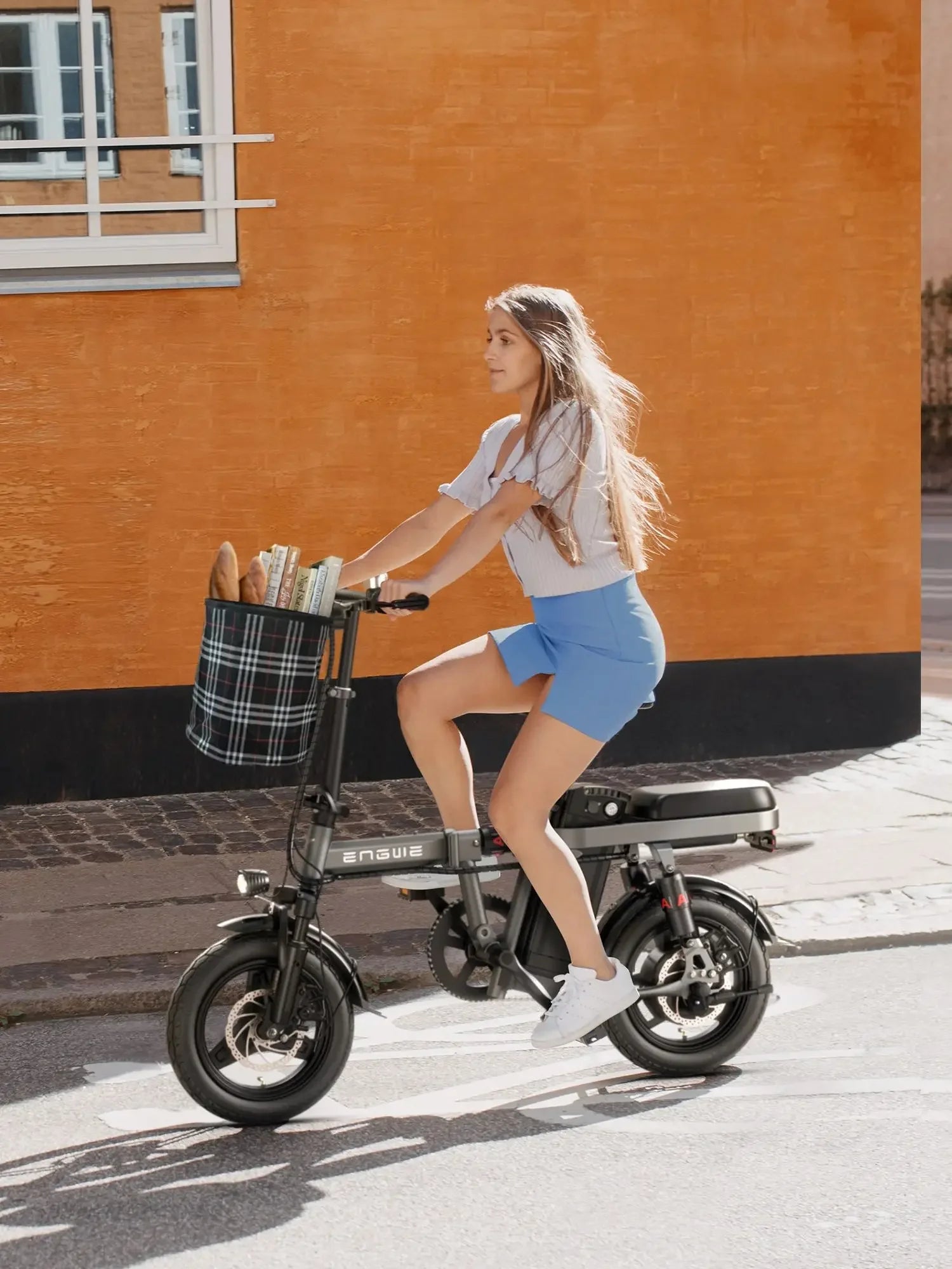 Woman riding foldable electric bike with basket in city street