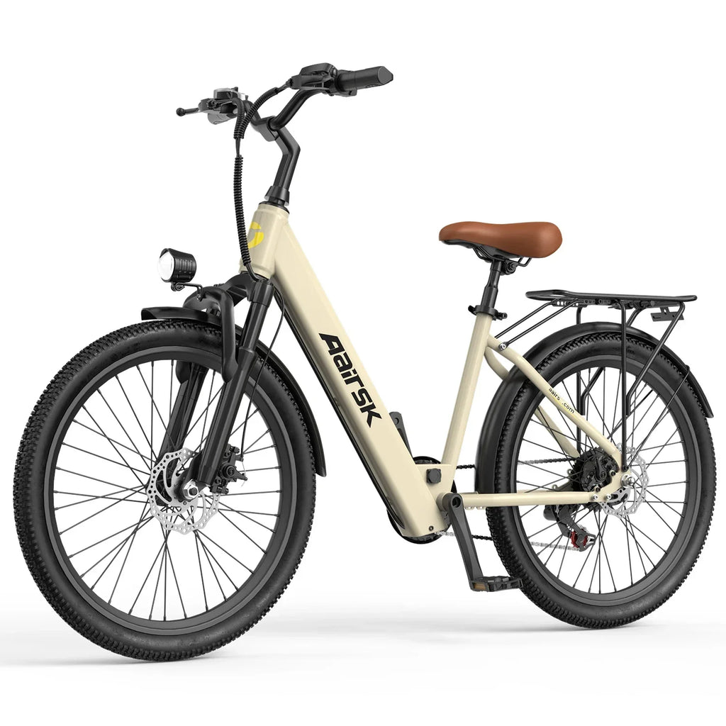 Beige electric bike with step-through frame, front light, rear rack, and all-terrain tires