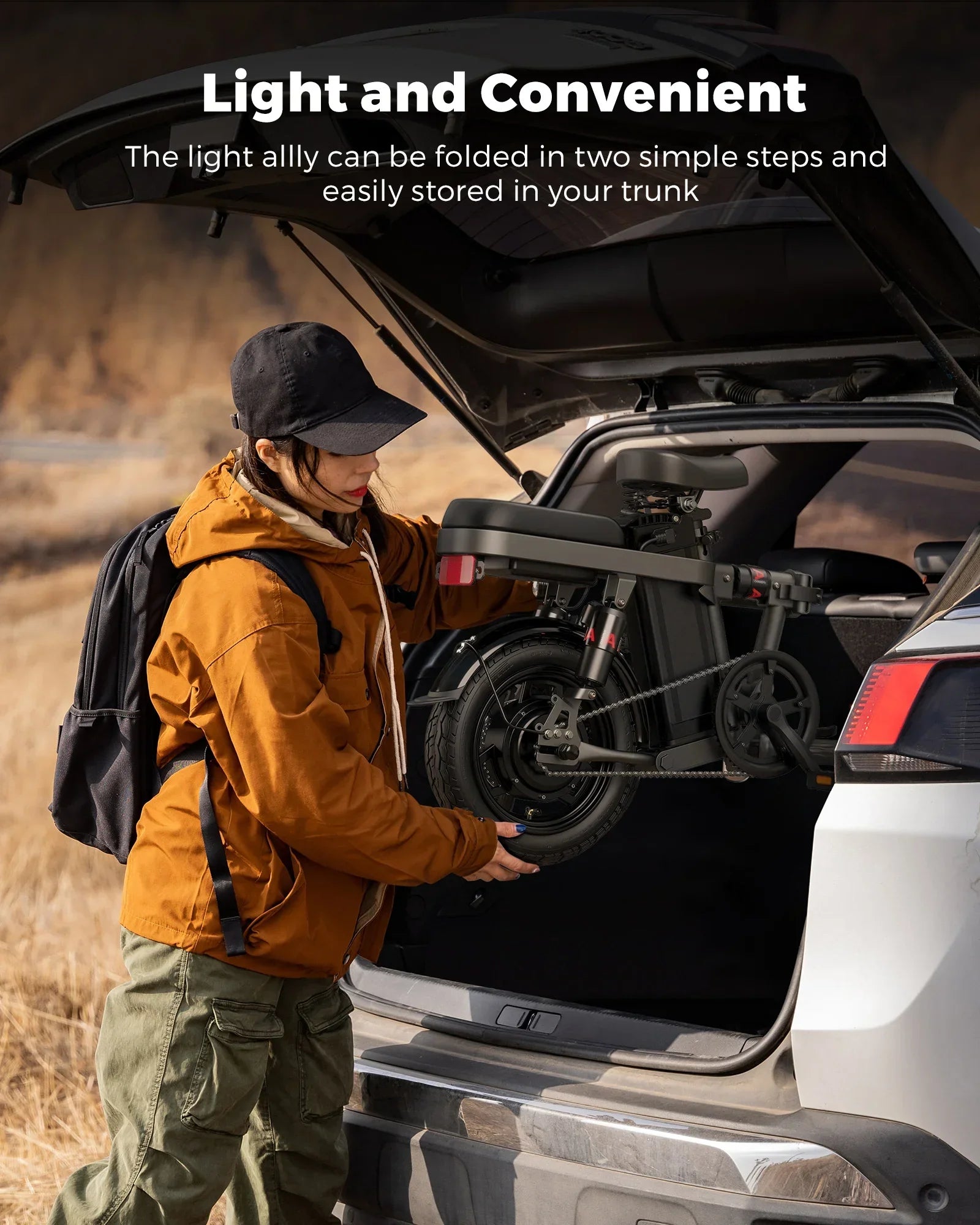 Person loading a folded electric bike into a car trunk outdoors